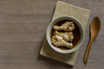 top view of chicken drumette soup in a ceramic bowl on wooden table. asian style food concept.