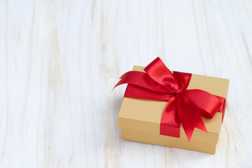 gift box golden new year or Christmas Packed present container with red ribbon on Vintage white wooden board background for holiday concept with copy space, top view pattern.