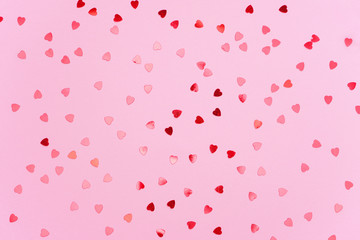 Red heart shape confetti pattern on light pink background. Valentine, love, wedding concept. Top view, flat lay