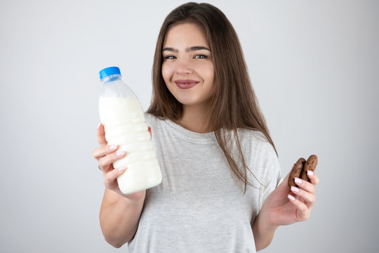 brunette woman in bra holding bottle and pouring milk on bust