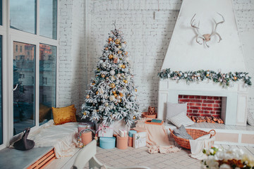 Christmas interior design in white colors. White wooden floor, christmas tree with ornaments, gifts and fireplace. Christmas cosiness.