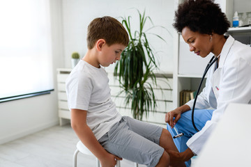 Woman African American doctor general practitioner examining child's patellar knee-jerk reflex