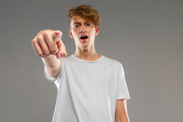 Young caucasian man in white t-shirt posing and gesticulating on camera isolated on grey background
