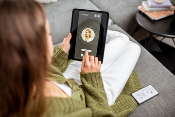 Woman making video call to a doctor using digital tablet, feeling bad at home. Concept of...