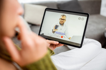 Woman talking with a doctor online using digital tablet, feeling bad at home. Concept of telemedicine and patient counseling online