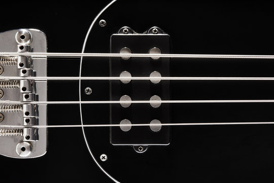 Close Up Detail Of A Black Bass Guitar Pickups, Frets And Bridge