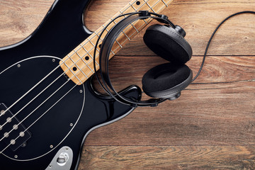 Black bass guitar with headphones on wooden table