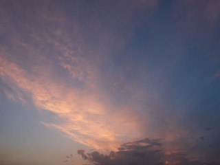 Bright multicolored clouds enlightened with rays of setting sun. Bright evening sky with pink, blue and purple cumulus, stratus and cirrus clouds