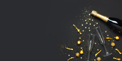 Christmas and New Year background. Champagne bottle champagne glasses golden christmas balls festive ribbons star confetti on black background top view. Flat lay holiday card. Party decorations 2020 © olgaarkhipenko