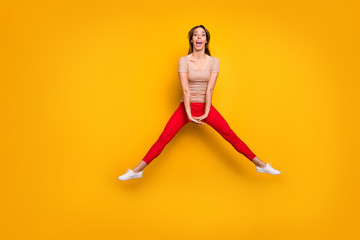 Fototapeta na wymiar Full size photo of funky carefree lady jumping high enjoy amazing summer sunny day free time wear casual striped t-shirt red trousers isolated yellow color background