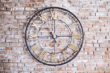 Round iron old fashioned clock on the brick wall. Five minutes to midnight.
