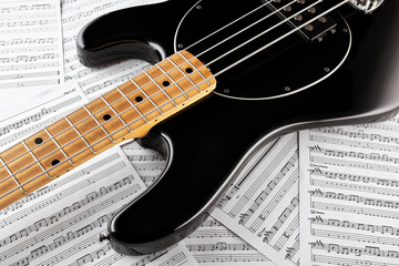 Fototapeta na wymiar Vintage black bass guitar on music sheets background