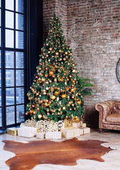 Interior with couch and Decorated Christmas tree in gold and yellow colors. Merry Christmas and Happy New Year!