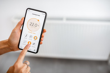 Controlling radiator heating temperature with a smart phone, close-up with radiator on the...