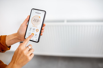 Controlling radiator heating temperature with a smart phone, close-up with radiator on the...