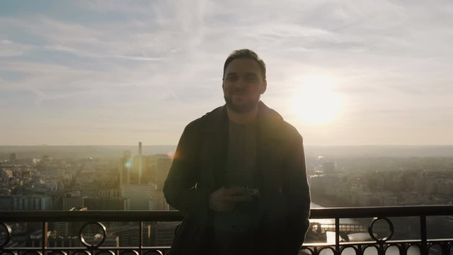 Young happy smiling Caucasian tourist man looking at camera on sunset sky panorama at Eiffel Tower, Paris slow motion.