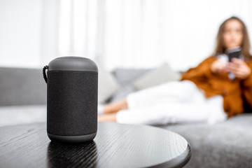 Smart wireless column with a young woman controlling home devices with a voice commands on the...