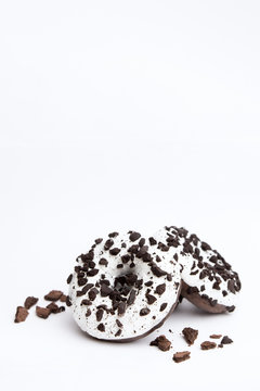 Delicious Fresh Donuts Black And White Color With White Icing And Chocolate Chips With Paper Glass Of Coffe Closeup On A White Background