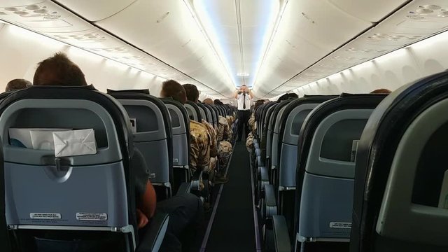 Air steward shows passengers use of seat belt. Zoom in shot