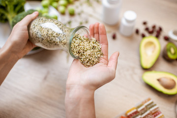 Holding hemp seeds at the table with healthy vegan food ingredients and supplements, top view....