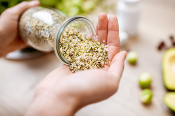 Holding hemp seeds at the table with healthy vegan food ingredients and supplements, top view. Concept of Marijuana as a new trend in food and cosmetic industry