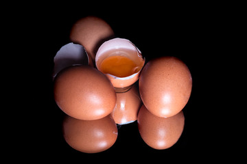 Fresh organic eggs with reflection on shiny black background