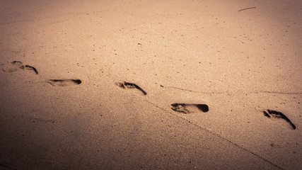 Close up textured background footprint of a man walking on the sand at the beach