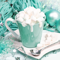Xmas still life with cocoa or chocolate with cream and marshmallows, knitted scarf, Christmas decor in trendy color 2020 Aqua Menthe.