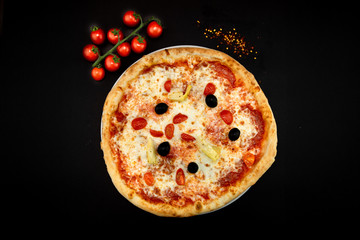 Isolated round pizza on black background with tomatoes