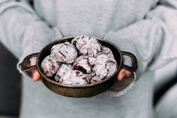 Chocolate Crinkle Cookies in an old plate in a girl's hands