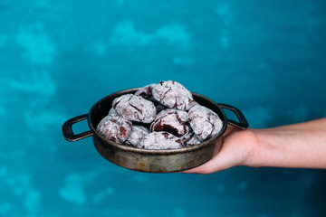 Chocolate Crinkle Cookies in an old plate in a girl's hands