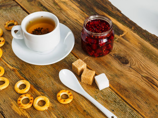 Herbal tea, raspberry jam and bagels on an old wooden table