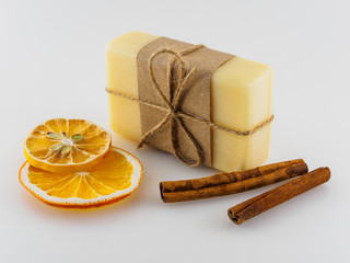 Yellow handmade soap, dry orange slices and cinnamon sticks on a white background