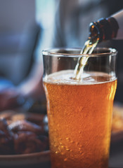 pouring beer in glass from bottle on bar or pub
