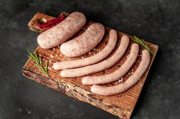 Raw grilled sausages with spices and rosemary, on a stone table, cooking concept