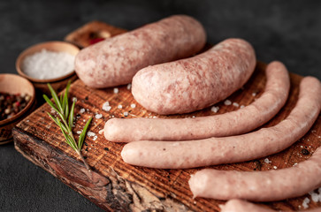 Raw grilled sausages with spices and rosemary, on a stone table, cooking concept