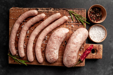 Raw grilled sausages with spices and rosemary, on a stone table, cooking concept
