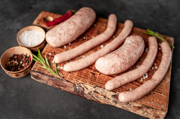 Raw grilled sausages with spices and rosemary, on a stone table, cooking concept