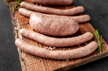 Raw grilled sausages with spices and rosemary, on a stone table, cooking concept