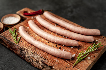 Raw grilled sausages with spices and rosemary, on a stone table, cooking concept