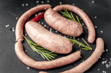 Raw grilled sausages with spices and rosemary, on a stone table, cooking concept