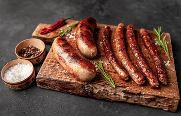 different grilled sausages with spices and rosemary, on a stone table ready to eat