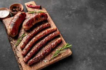 different fried sausages with spices and rosemary, on a stone table, ready to eat with copy space for your text