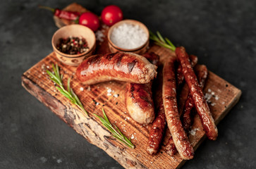 different grilled sausages with spices and rosemary, on a stone table ready to eat