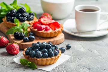 Fresh homemade berrie tarts with blueberries, blackberry and strawberries on gray background