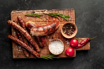 Fototapeta na wymiar different grilled sausages with spices and rosemary, on a stone table ready to eat