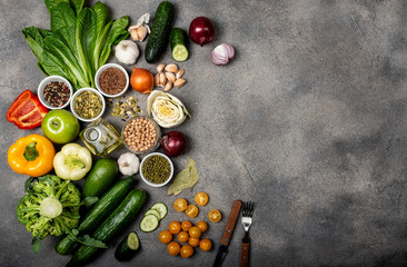 set of different vegetables and spices, ingredients for preparing a healthy vegetarian food. Top view on a gray background with space for text.
