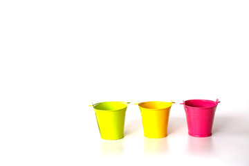 Close-up yellow , pink , green bucket on white background.