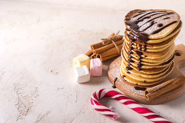  Fresh sweet pancakes with chocolate jam, cinnamon sticks and marshmallows on a gray background with place for your text.