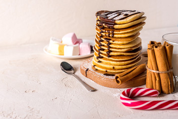  Fresh sweet pancakes with chocolate jam, cinnamon sticks and marshmallows on a gray background with place for your text.